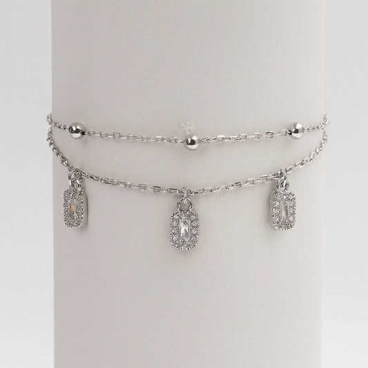 Silver bracelet with charms on a white round stand