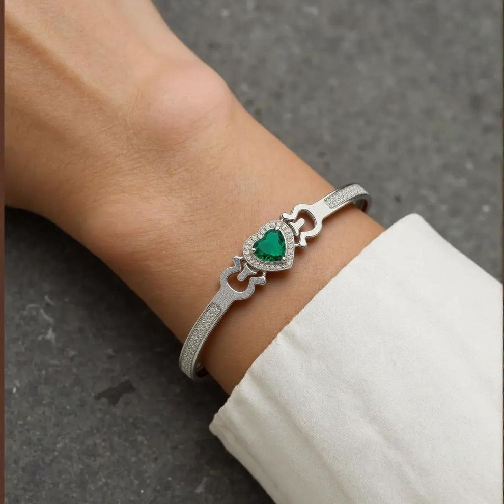 Silver bracelet with a green gemstone on a wrist against a gray background