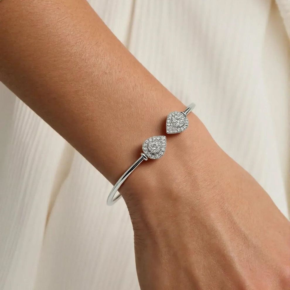 A women in white office outfit wearing silver bracelet with two diamond-like stones 