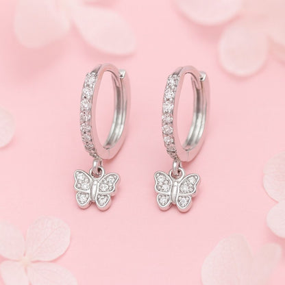 Silver hoop earrings with butterfly charms on a pink floral background