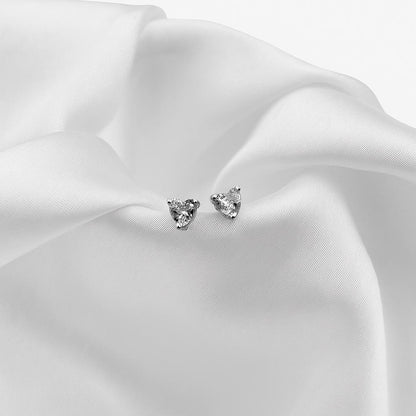 Pair of silver heart-shaped stud earrings on white fabric