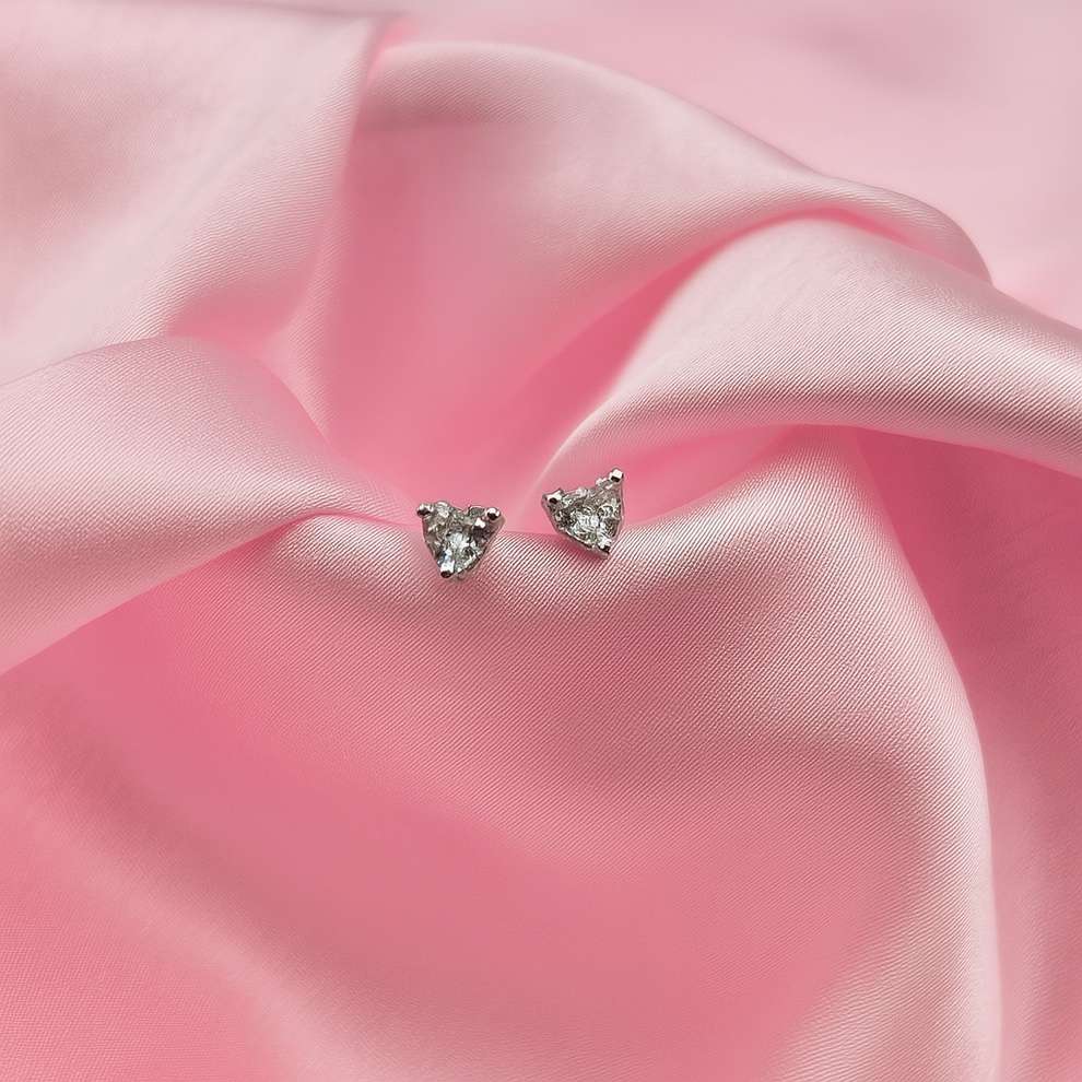 Heart-shaped stud earrings on a pink fabric background