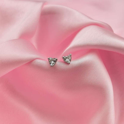 Heart-shaped stud earrings on a pink fabric background