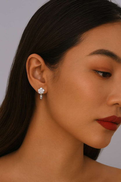 Close-up of a modern woman wearing a floral silver earring against a neutral background