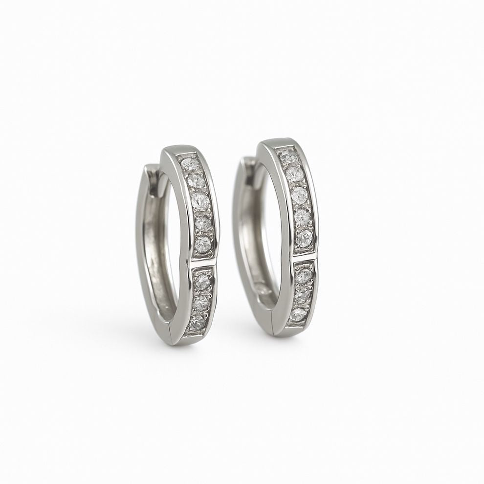 Pair of silver hoop earrings with embedded white stone on a white background