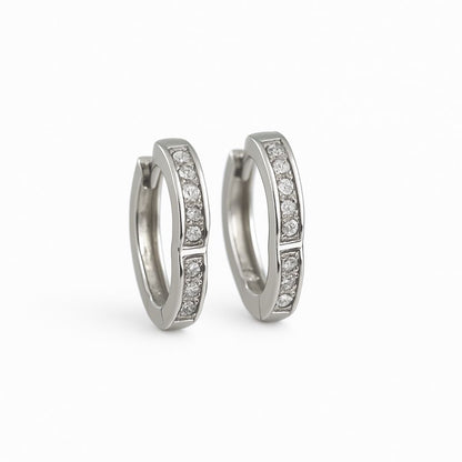 Pair of silver hoop earrings with embedded white stone on a white background
