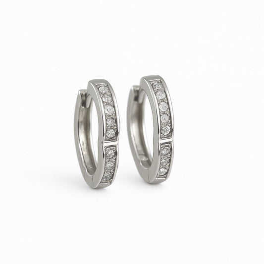 Pair of silver hoop earrings with embedded white stone on a white background