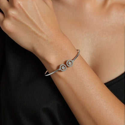 Silver bracelet with circular design on a wrist against a dark background