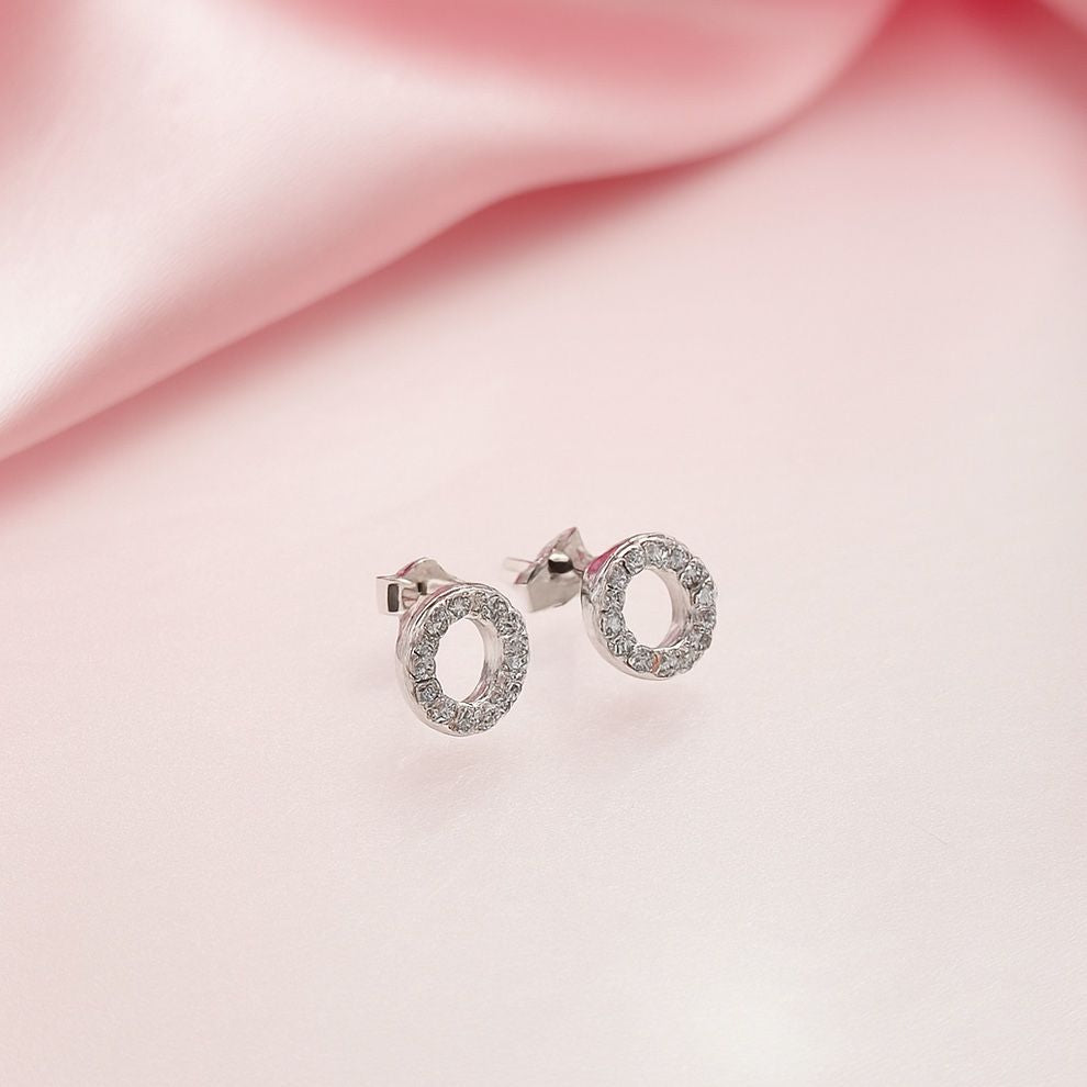 Silver earrings with oval design on a pink fabric background