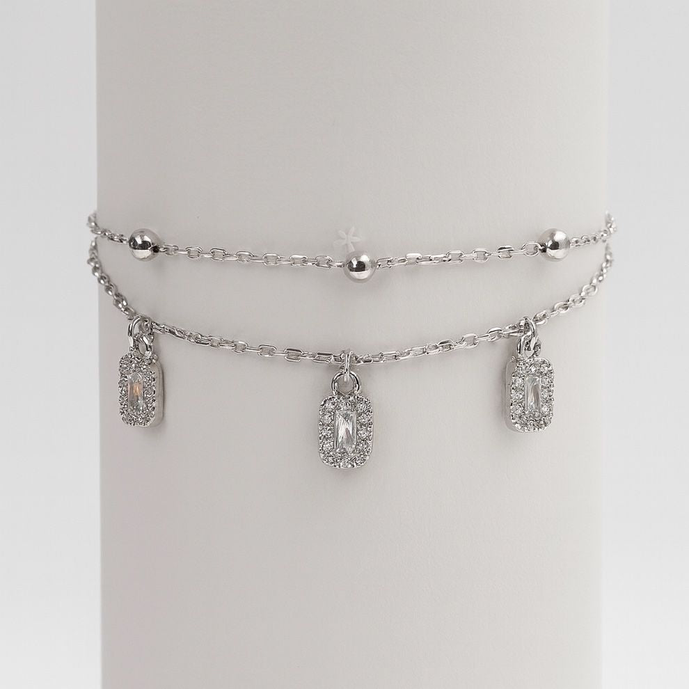 Silver bracelet with charms on a white round stand