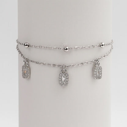 Silver bracelet with charms on a white round stand