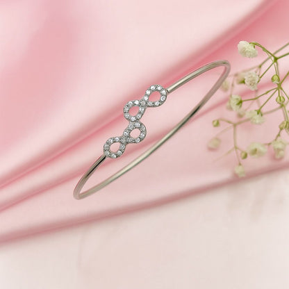 Silver bracelet with interlocking rings on a pink fabric background