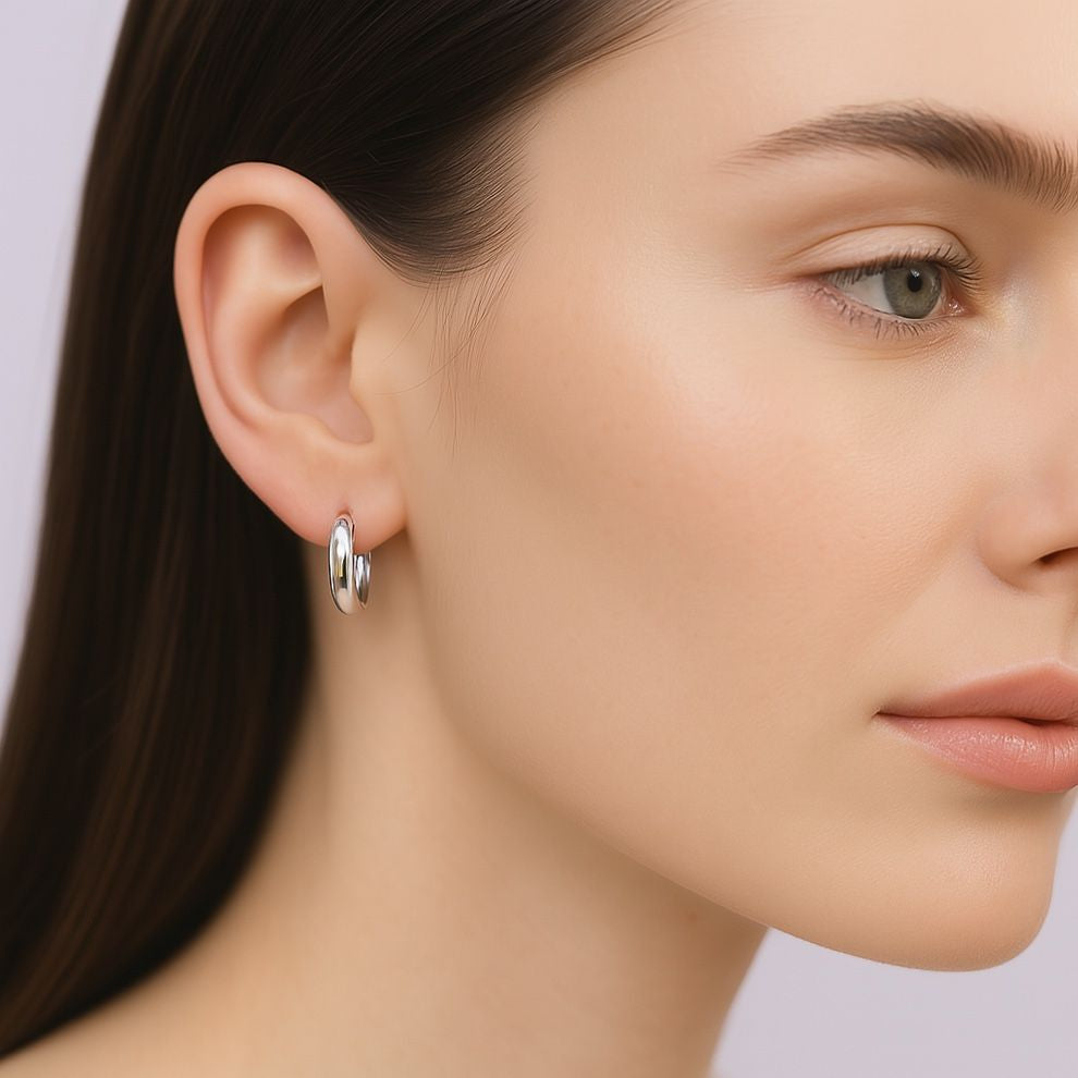 Close-up of a woman wearing silver hoop earrings with a neutral background