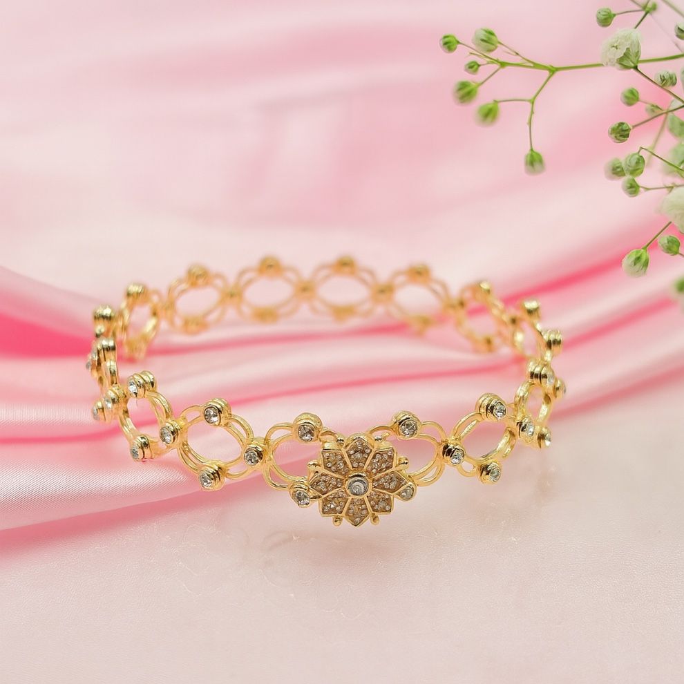 Gold bracelet with floral design on a pink fabric background