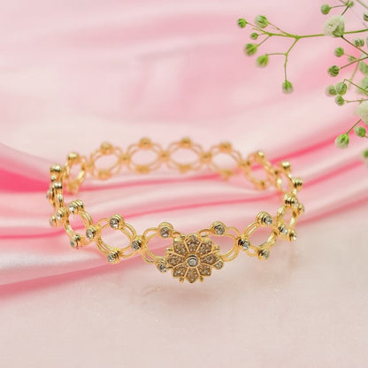 Gold bracelet with floral design on a pink fabric background