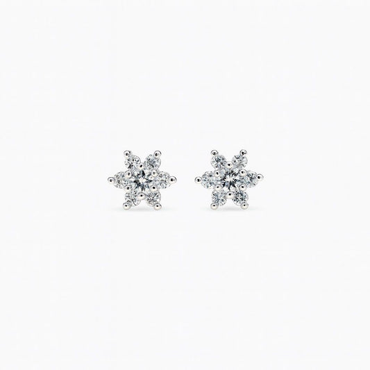 Pair of snowflake-shaped diamond earrings on a white background