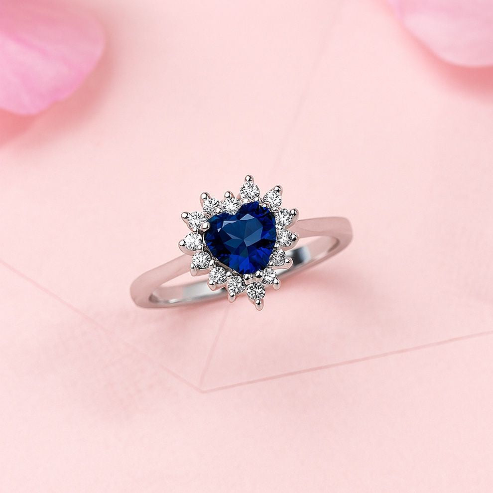 Silver ring with a blue heart-shaped gemstone on a pink floral background