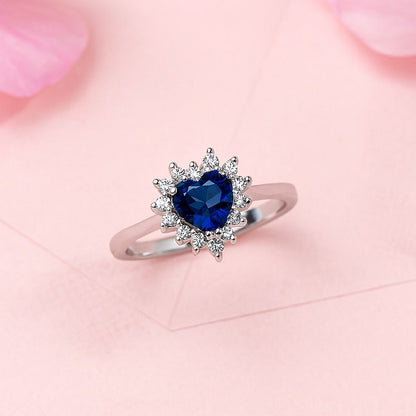 Silver ring with a blue heart-shaped gemstone on a pink floral background