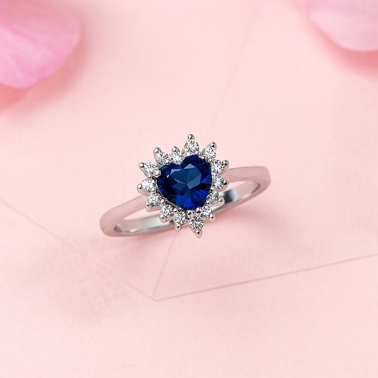 Silver ring with a blue heart-shaped gemstone on a pink floral background