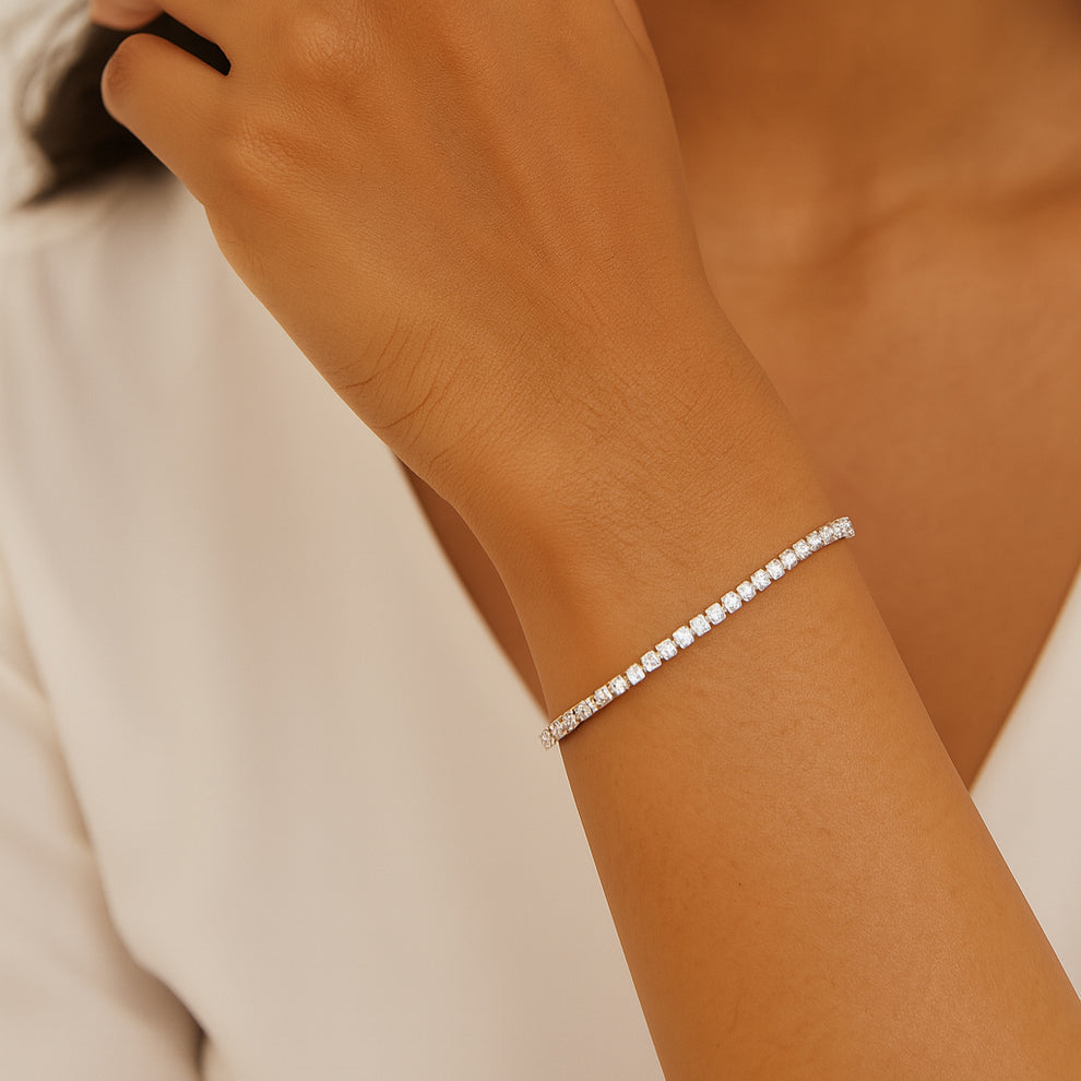 Silver tennis bracelet on a women's wrist with a neutral background