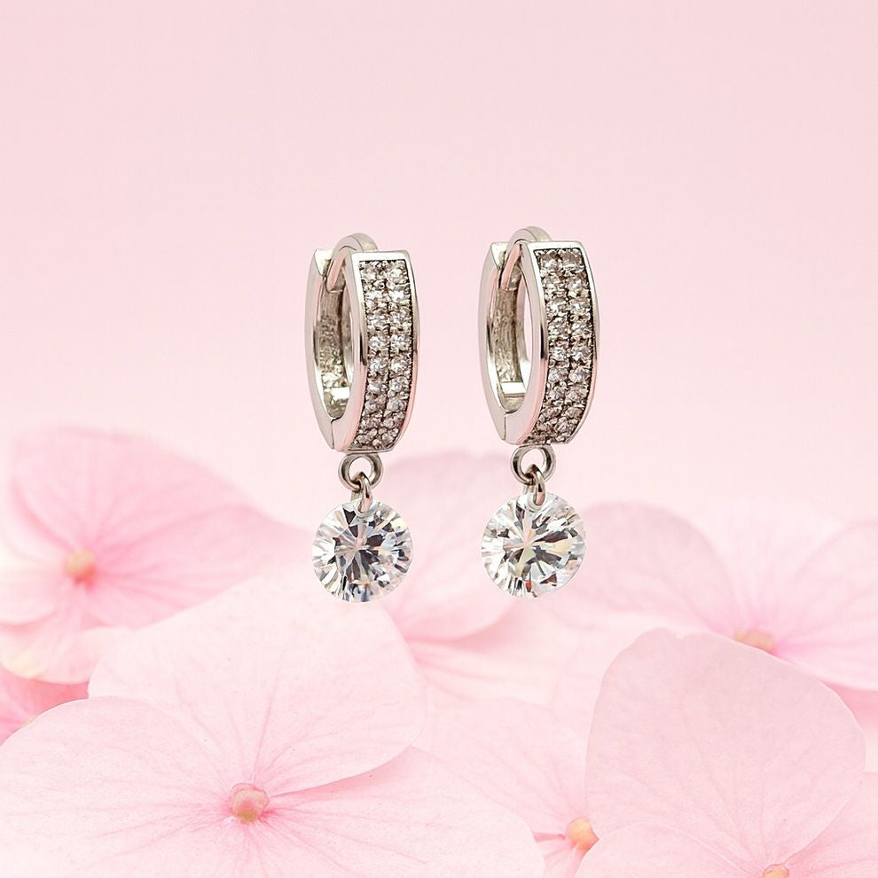 Silver hoop earrings with crystal drops on a pink floral background