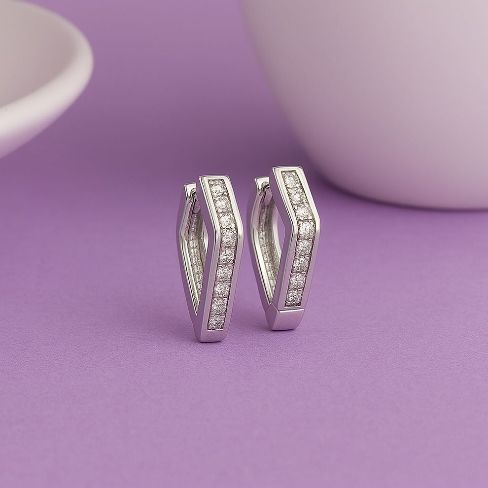 Silver hoop earrings with embedded stones on a purple background