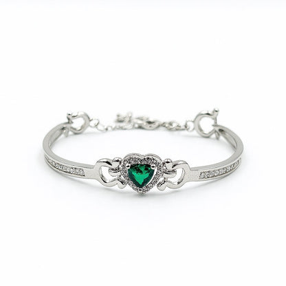 Silver bracelet with a heart-shaped green gemstone on a white background