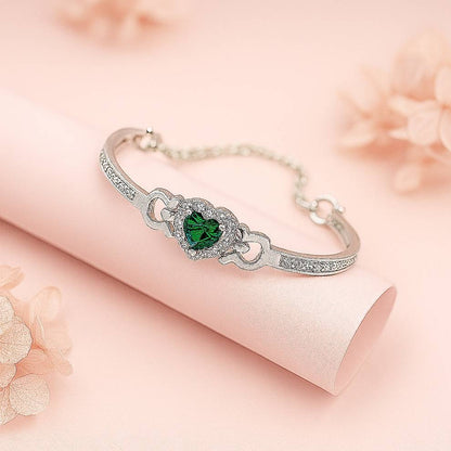 Silver bracelet with a green gemstone on a soft pink background