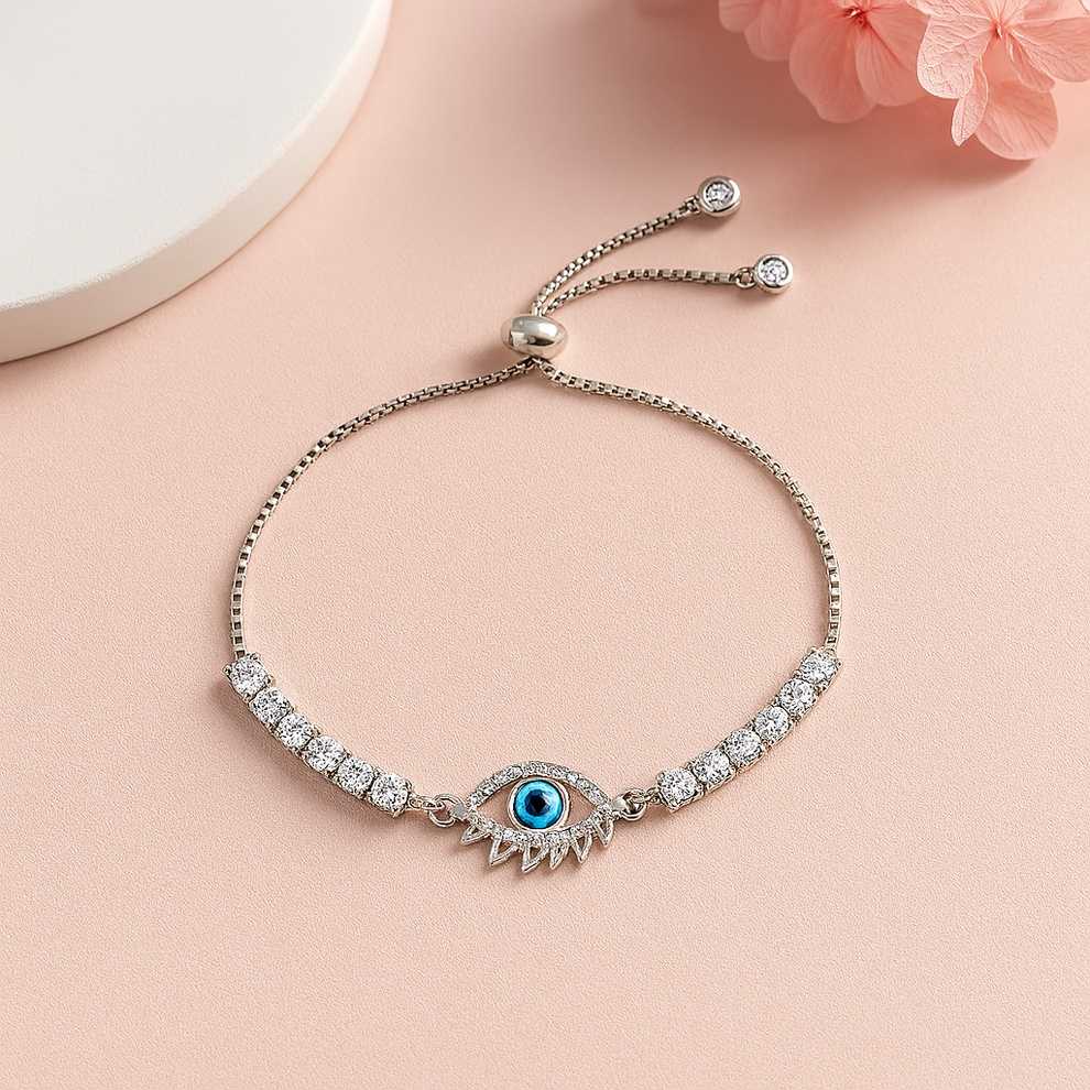 Silver bracelet with evil eye design on a pink surface