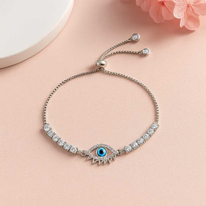 Silver bracelet with evil eye design on a pink surface
