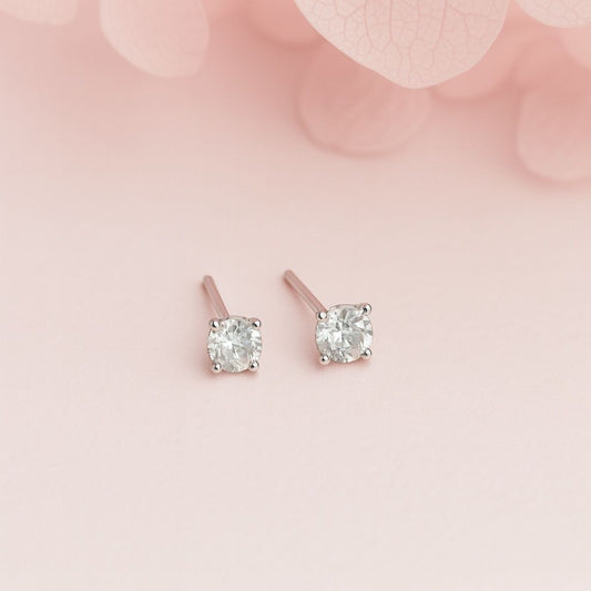 Pair of silver  stud earrings on a soft pink background