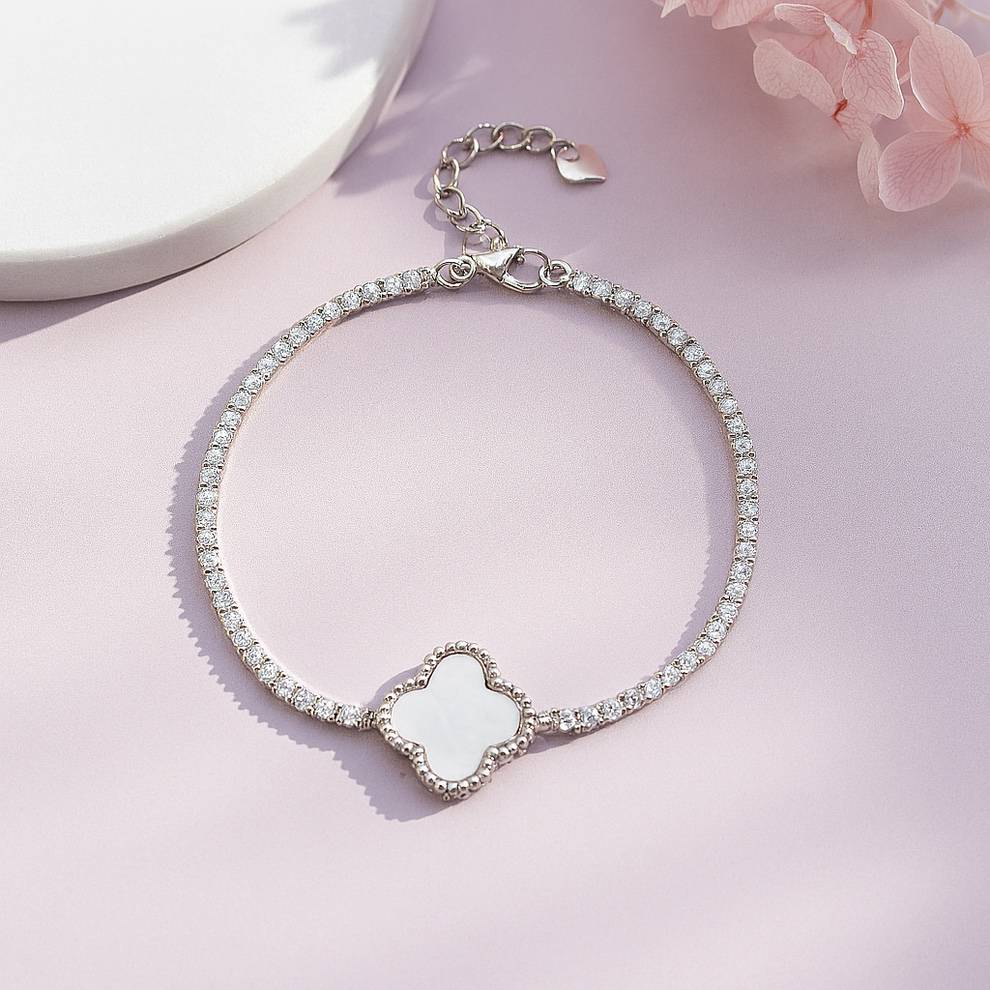 Silver bracelet with a floral-shaped charm on a pink background