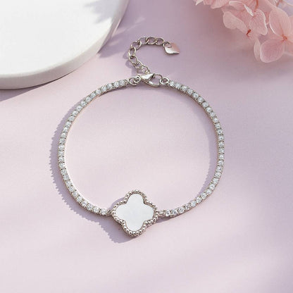 Silver bracelet with a floral-shaped charm on a pink background