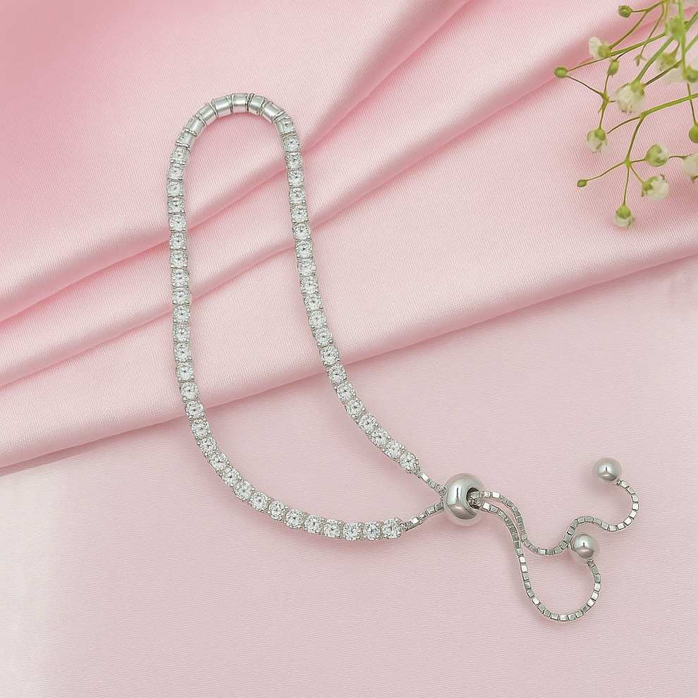 Silver tennis bracelet with clear stones on a pink fabric background