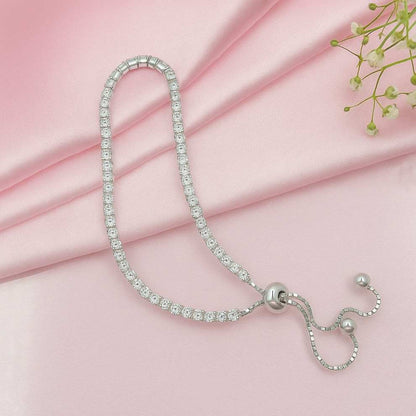 Silver tennis bracelet with clear stones on a pink fabric background