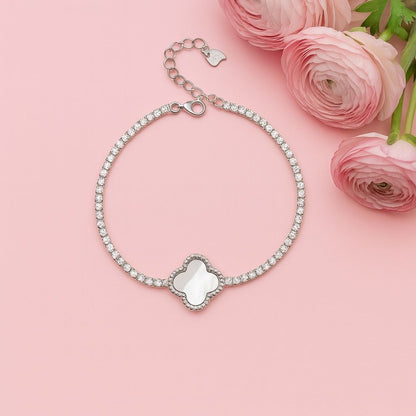 Silver bracelet with heart charm on a pink background with pink flowers