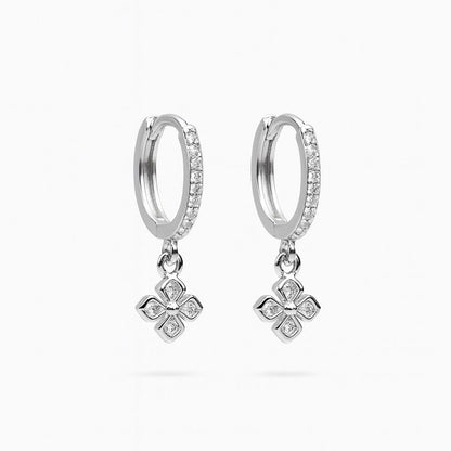 Silver hoop earrings with clover-shaped charms on a white background