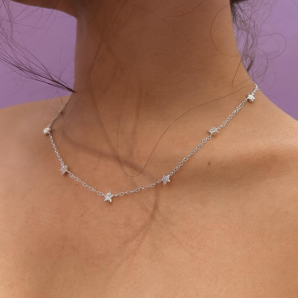 Silver necklace on a person's neck against a purple background