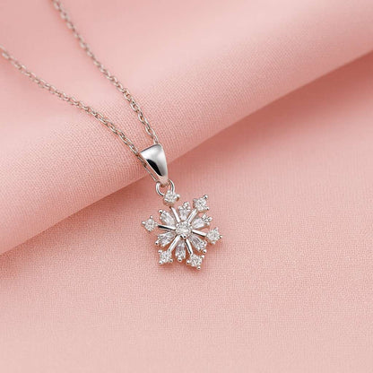 Silver snowflake pendant necklace on a pink fabric background