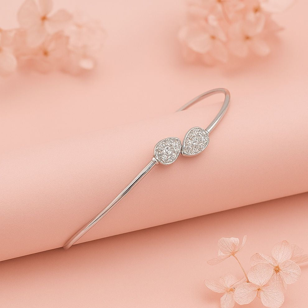 Silver bracelet with two decorative elements on a soft pink background with flowers.