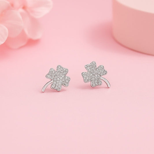 Silver four-leaf clover sterling silver earrings on a pink background