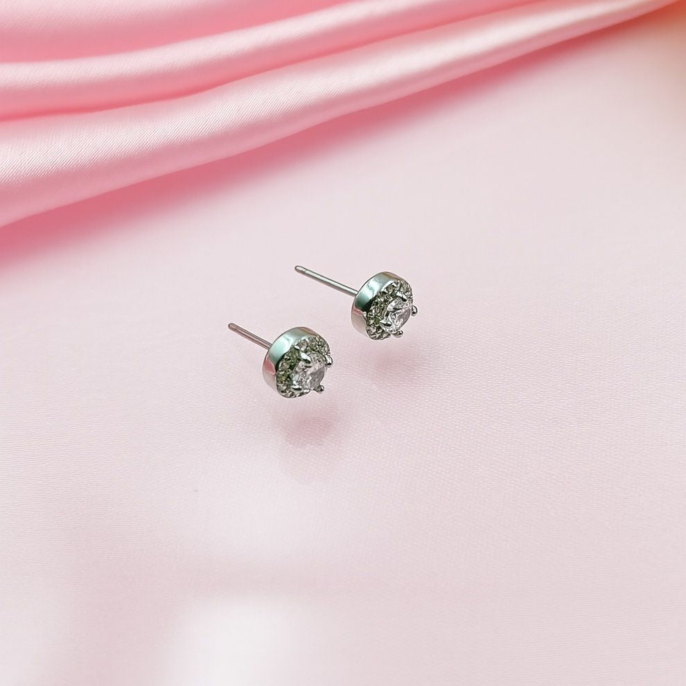 Silver stud earrings on a pink satin background