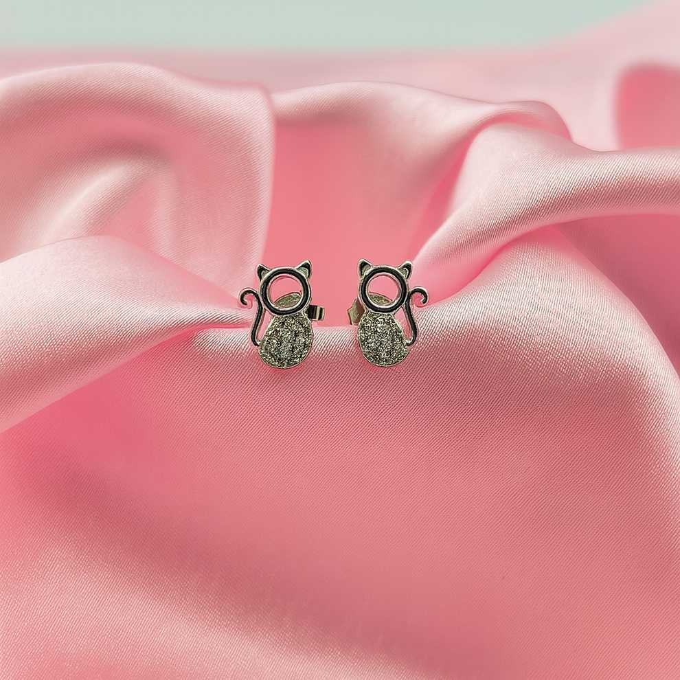 Cat-shaped earrings on a pink fabric background