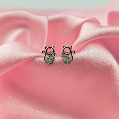 Cat-shaped earrings on a pink fabric background