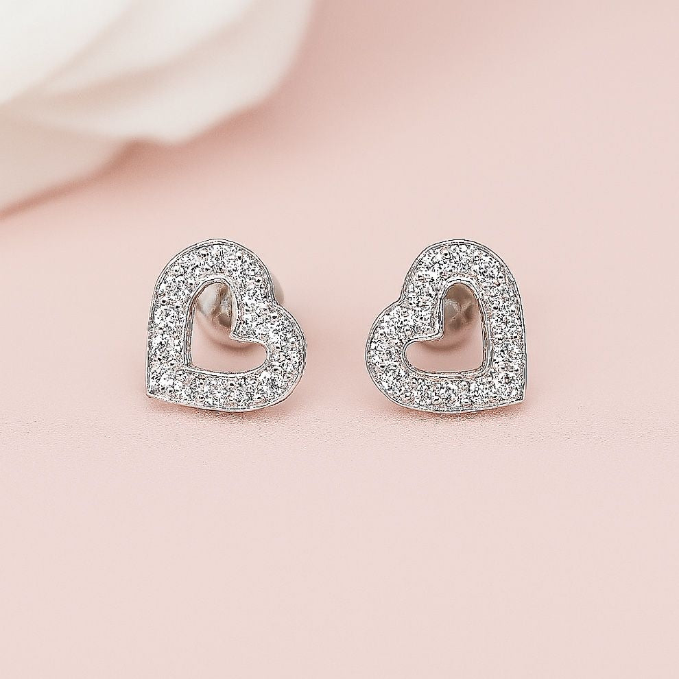 Heart-shaped earrings with clear stones on a light pink background