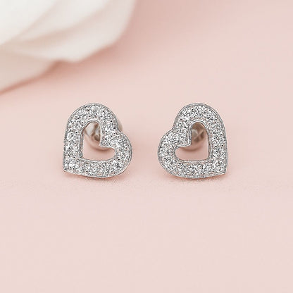 Heart-shaped earrings with clear stones on a light pink background