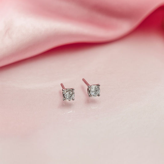 Pair of silver stud earrings on a pink fabric background