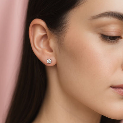 Close-up of a modern woman wearing silver stud earrings with a soft pink background
