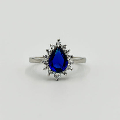Silver ring with a blue teardrop-shaped gemstone on a light gray background