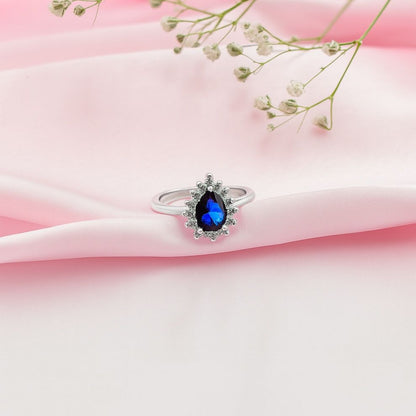 Silver ring with a blue gemstone on pink fabric